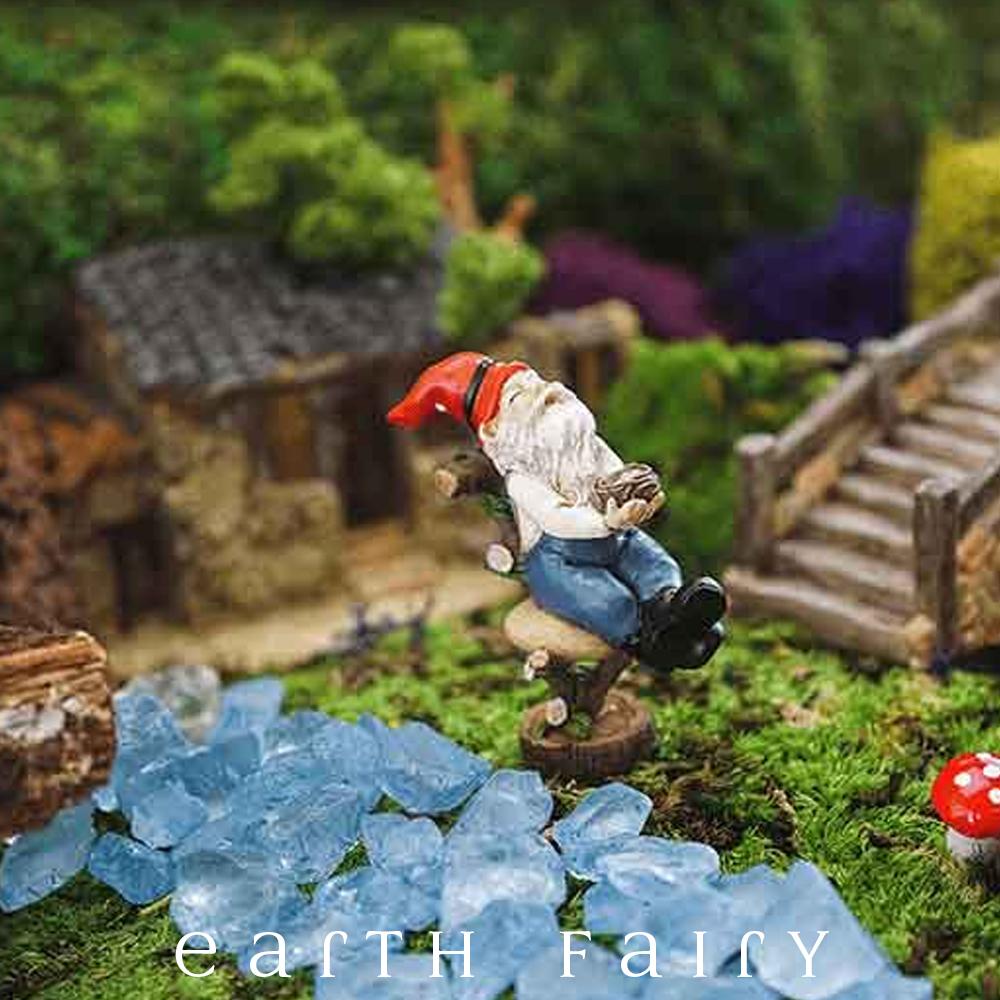 miniature polyresin gnome figurine, posed laying back on a log hewn chair, black boots, blue overalls, red pointy hat and clasping a nest full of eggs