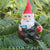 miniature polyresin gnome figurine, wearing boots, red pants, green coat and red pointy hat, posed sitting with a drink and holding an apple